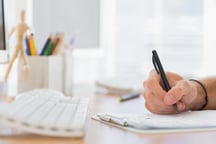 Close up of a hand writing in a modern office on a clipboard