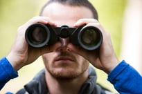 Close-up of male hiker looking through binoculars in forest-1