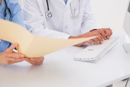 Doctors using computer looking at files in medical office