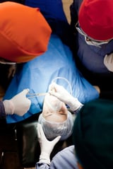Group of doctors operating on a female patient