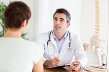 Male Doctor writing something down while patient is talking in a room-1