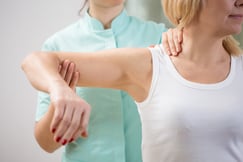 Physical therapist diagnosing patient with painful arm