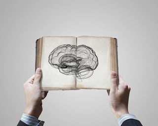 Close up of male hands holding opened book with brain picture.jpeg