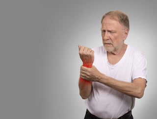 Suffering from pain and rheumatism. Closeup elderly, senior old man looking miserable in great excruciating hand ache painful wrist colored in red isolated on gray background. Health issues problems.jpeg