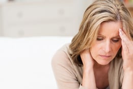 Woman suffering from stress or a headache grimacing in pain as she holds the back of her neck with her other hand to her temple, with copyspace-1